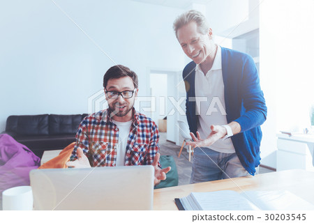 Positive colleagues using laptop in the office Positive colleagues using laptop in the office 30203545
