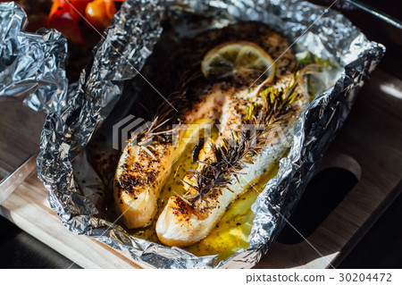 fish steak baked with lemon and herbs in foil. 30204472