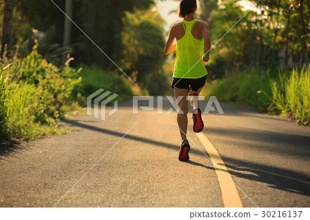 Young woman running on tropical forest trail Young woman running on tropical forest trail 30216137