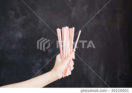 Woman hand hold cocktail straw on black background Woman hand hold cocktail straw on black background 30220801