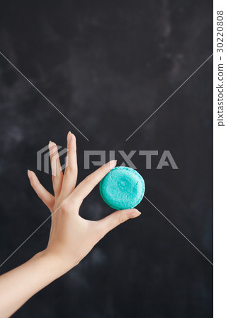 Blue macaroon almond cake in a woman's hand Blue macaroon almond cake in a woman's hand 30220808