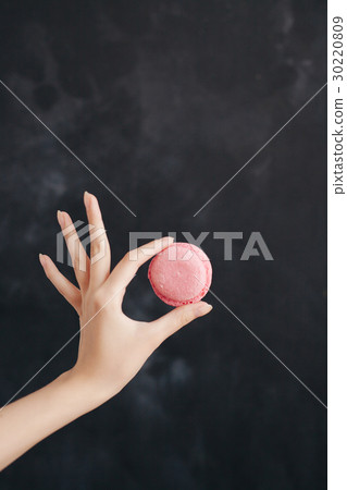 Pink macaroon almond cake in a woman's hand Pink macaroon almond cake in a woman's hand 30220809