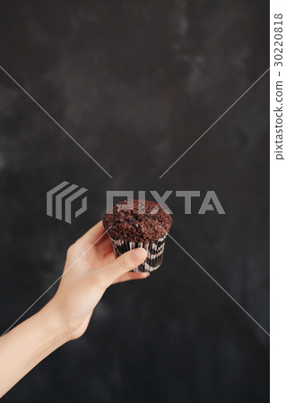 Woman holding a chocolate muffin on black Woman holding a chocolate muffin on black 30220818