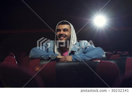 Happy smiling young man watching movie in theater Happy smiling young man watching movie in theater 30232141