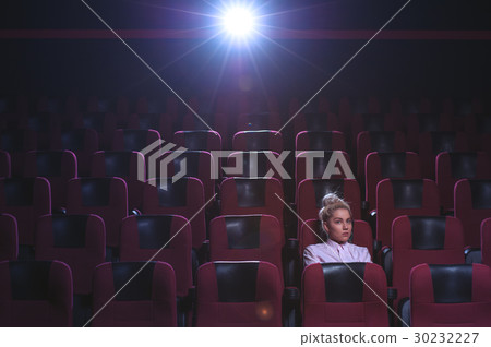 Blonde girl watching movie in empty theater Blonde girl watching movie in empty theater 30232227