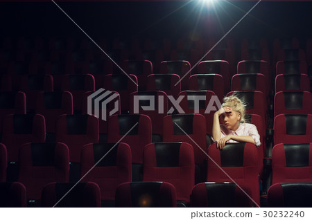 Young caucasian woman sitting in cinema theater 30232240