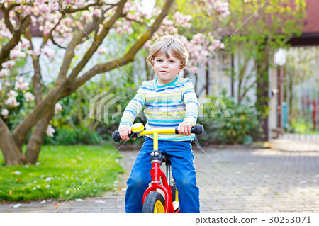 Adorable little kid boy driving his first bike or Adorable little kid boy driving his first bike or 30253071