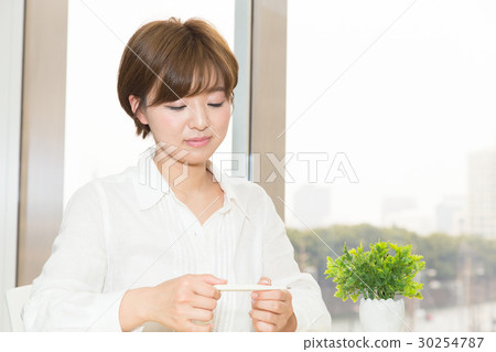A woman with a thermometer A woman with a thermometer 30254787