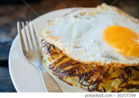 Potato pancakes with fried eggs are served with a 30257199