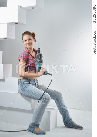 Beautiful young woman uses an electric drill 30259396