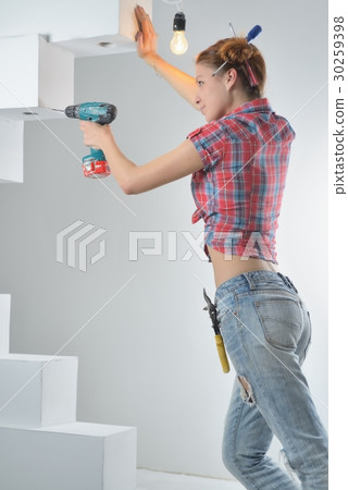 Beautiful young woman uses an electric drill 30259398