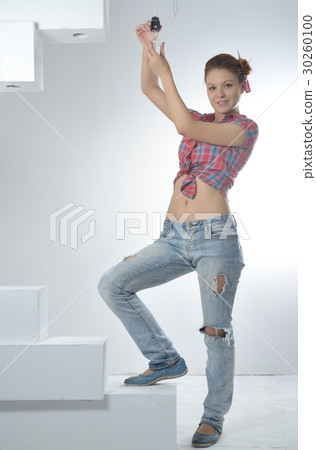 Young beautiful woman twists a bulb Young beautiful woman twists a bulb 30260100