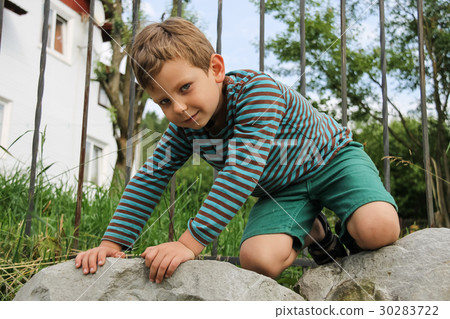 Little boy in striped sweater and shorts on rocks 30283722