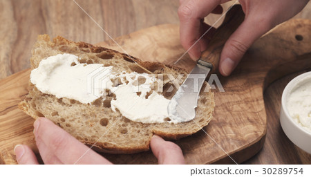 spreading ricotta cheese on fresh rustic bread spreading ricotta cheese on fresh rustic bread 30289754