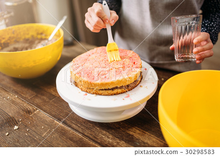Woman cook hands smears filling for cake Woman cook hands smears filling for cake 30298583