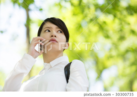 Business woman Conversation with a smartphone Low angle green background white shirt Business woman Conversation with a smartphone Low angle green background white shirt 30300735