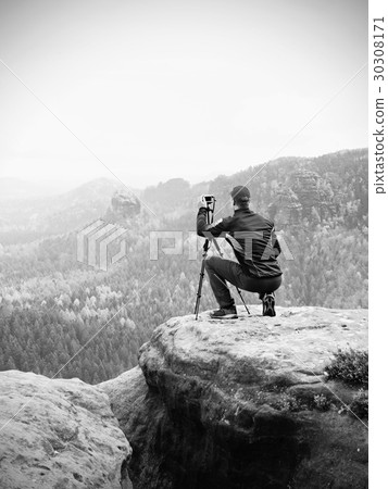 Outdoor photographer with tripod, camera on rock  30308171