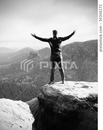 Alone hiker in red cap stand on the peak of rock 30308172