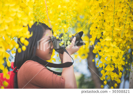 Asian girl take photo with blooming yellow flower 30308821