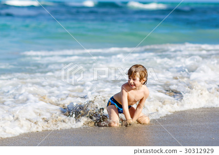 little blond kid boy having fun on ocean beach in little blond kid boy having fun on ocean beach in 30312929