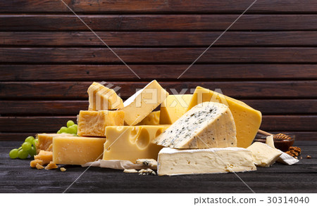 Various types of cheese on black wooden table. 30314040