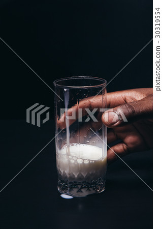 Hand of black man hold glass of white milk Hand of black man hold glass of white milk 30319554