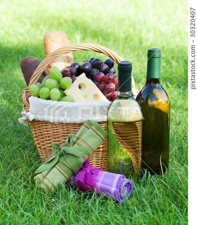 Outdoor picnic basket with wine on lawn 30320407