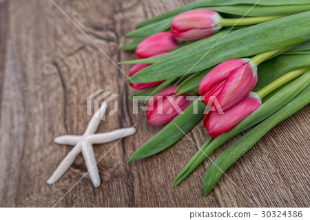 Starfish and tulips on a wooden background Starfish and tulips on a wooden background 30324386