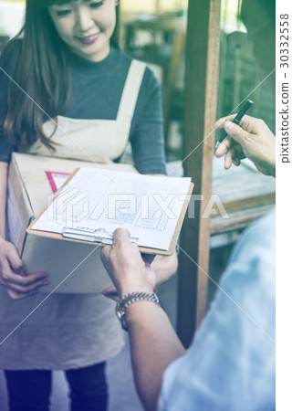 Young woman receive a parcel and sign the document Young woman receive a parcel and sign the document 30332558