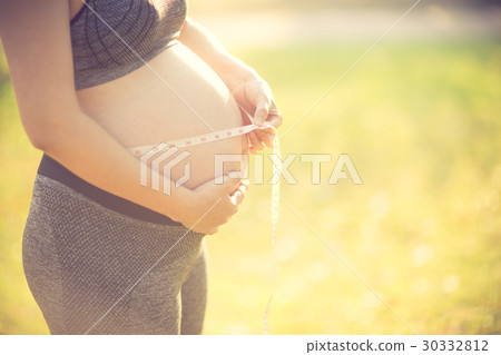 Pregnant woman measuring her belly Pregnant woman measuring her belly 30332812