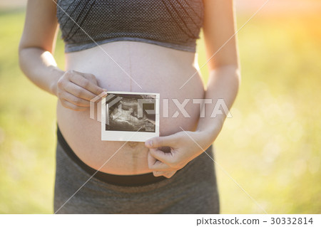 Pregnant woman holding ultrasound image Pregnant woman holding ultrasound image 30332814