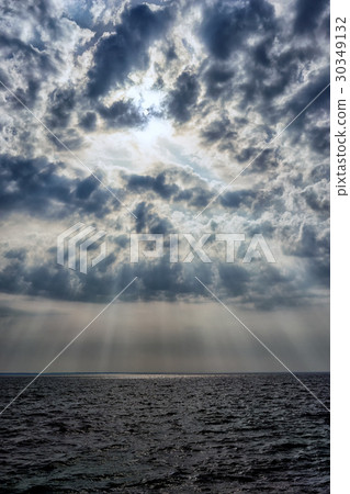 The sun behind the clouds over the sea 30349132