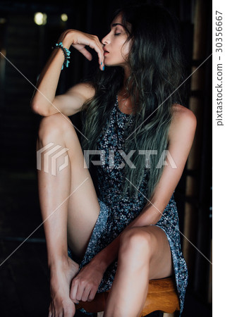 A charming young girl in a dress is sitting on a 30356667