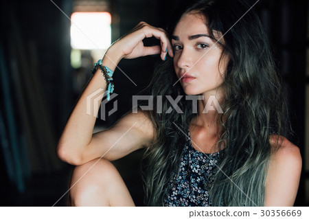 A charming young girl in a dress is sitting on a A charming young girl in a dress is sitting on a 30356669