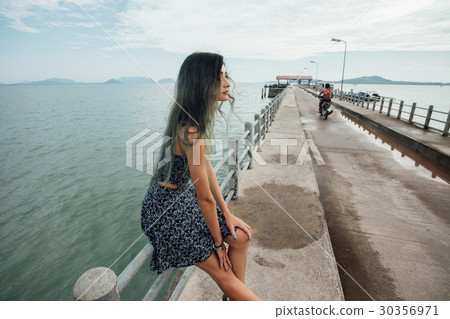 Young beautiful woman in dress sitting on the pier 30356971