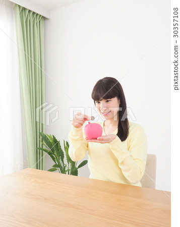 A woman who puts a coin in a pig's piggy bank A woman who puts a coin in a pig's piggy bank 30357108