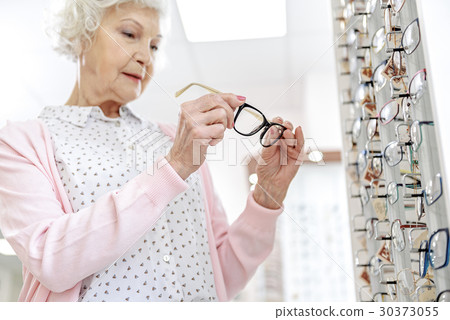 Concentrated mature woman keeping eyewear Concentrated mature woman keeping eyewear 30373055