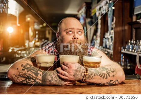 Pensive male embracing mugs of alcohol beverage 30373650