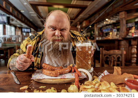 Rough fat male tasting frankfurters in pub 30374251