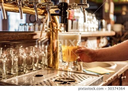 Male arm keeping pouring beer in alehouse 30374364