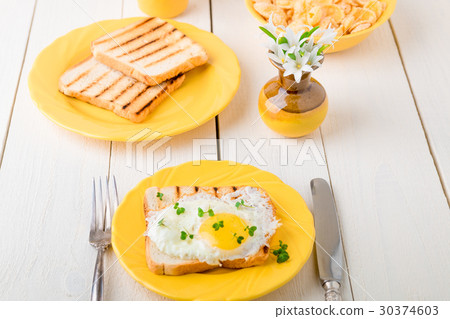Toast with egg in yellow plate near vase Toast with egg in yellow plate near vase 30374603