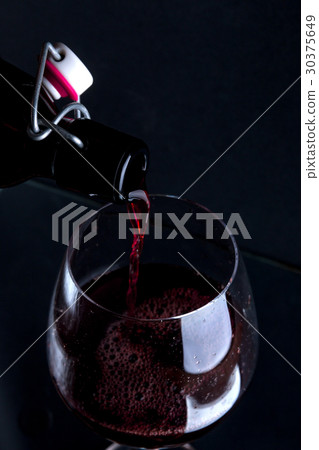Close up of red wine pouring in glass. 30375649