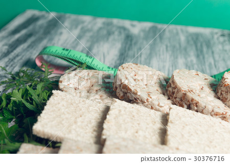 Pieces of crispbread near measuring tape and green 30376716