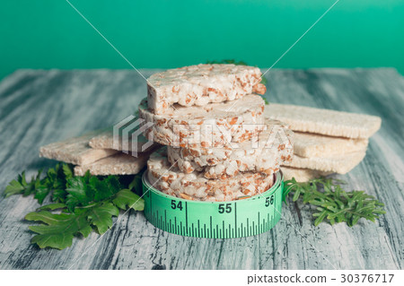 Pieces of crispbread near measuring tape and green 30376717