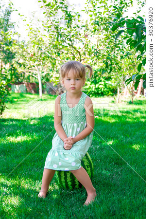 Little girl in green dress sitting on the waterm 30376920
