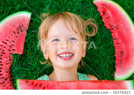 Little girl in green dress sitting on the waterm 30376921