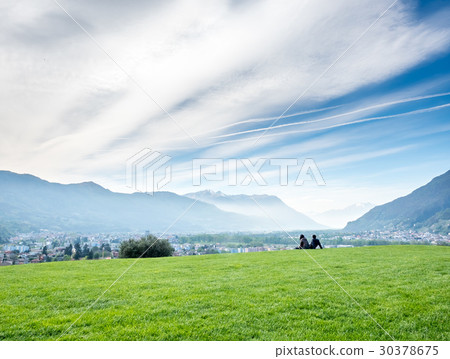 Two people sit on green grass 30378675