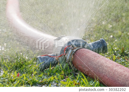 water leaking from hole in a industrial hose. 30382202