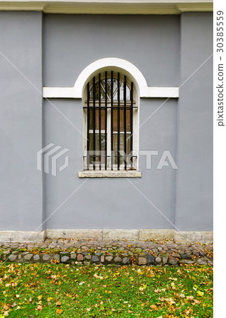 Window on the gray brick wall of old building 30385559