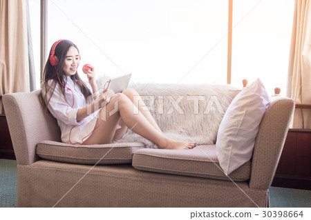 Young woman sitting in her bed and listening music. It's time fo Young woman sitting in her bed and listening music. It's time fo 30398664
